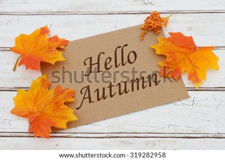 Hello Autumn Card, A brown card with words Hello Autumn over a distressed wood background with Autumn Leaves