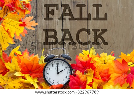 Fall Back Time Change, Autumn Leaves and Alarm Clock with grunge wood and words Fall Back