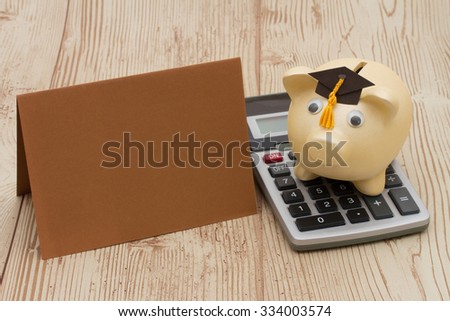 A golden with grad cap piggy bank, card and calculator on a wood background with copy space for your message
