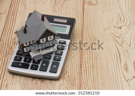 A gray house and calculator on wood background with copy space for your message