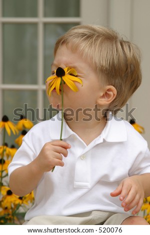 boy trying to smell flower