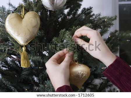Person hanging ornaments on Christmas tree