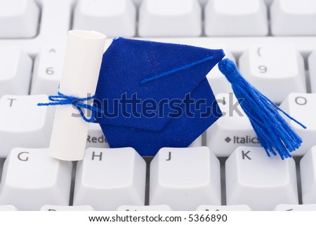 A blue graduation cap and diploma on a keyboard background