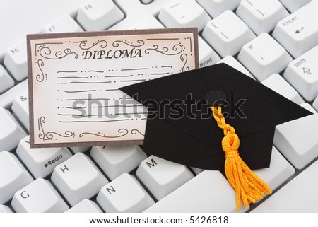 A black graduation cap and diploma with a keyboard on an isolated background