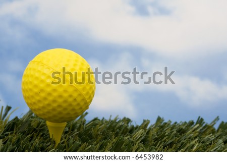 Yellow golf ball on tee with sky background