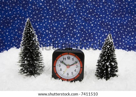 Clock sitting in snow with tree with a winter night background