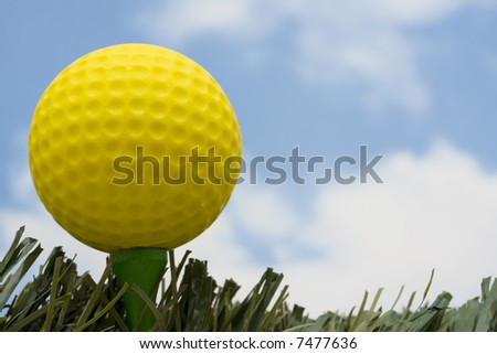 Yellow golf ball on tee with sky background