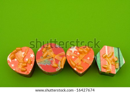 Four different shaped presents with ribbons on green background, looking for gift ideas