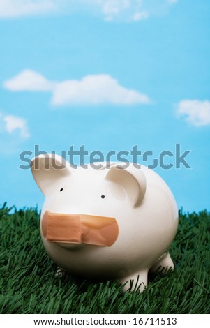 Piggy bank with adhesive bandage on mouth on grass with sky background, investment trouble