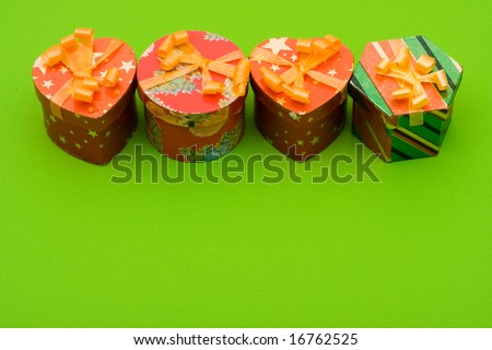 Four different shaped presents with ribbons on green background, looking for gift ideas
