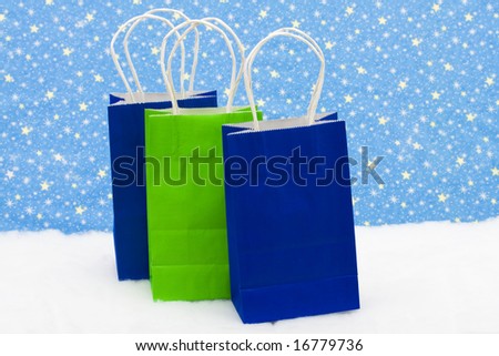 Three colourful gift bags on snow with star background, gift bag trio