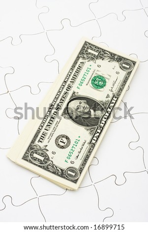 Puzzle with a stack of dollar bills sitting on it. understanding finances