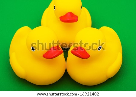 Three rubber ducks on green background, rubber ducks