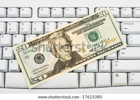 Twenty dollar bill sitting on grey keyboard, spending money online