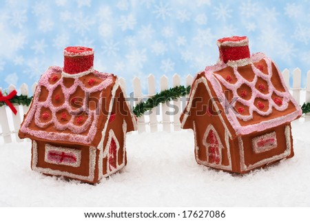 Two gingerbread houses and white picket fence with green garland and red bow, merry Christmas