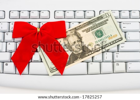 Twenty dollar bill sitting on grey keyboard with red velvet bow, spending money online