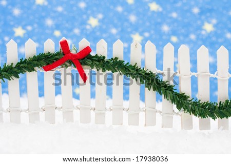 White picket fence with green garland and red bow, merry Christmas