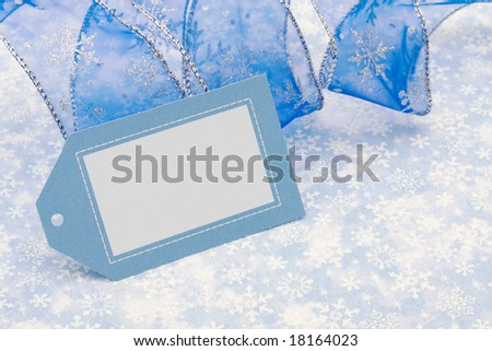 Blank gift tag with blue ribbon on blue snowflake background, merry Christmas