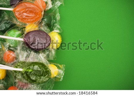 Suckers and bubble gum making border on green background, Halloween candy border