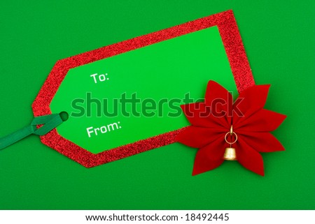Poinsettia flower with blank green gift tag on green background â?? holiday gift
