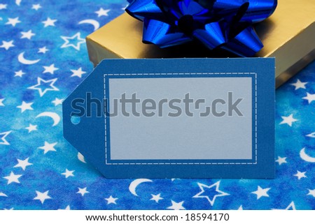 Gold present with blue bow and blank gift tag on moon and star background, present
