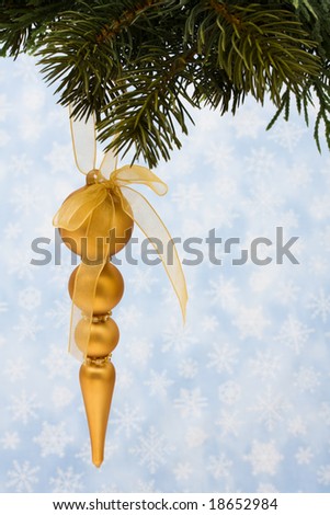 Christmas tree limb with gold glass ornaments on snowflake background, Christmas tree