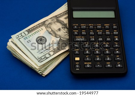 Black calculator with stack of twenty dollar bills on blue background, calculating interest