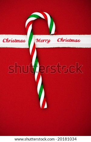 Candy cane with merry Christmas ribbon on red background, candy cane