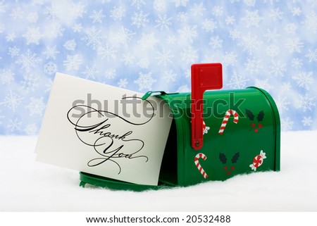 Green mailbox with white thank you card and the flag up sitting on snow with a snowflake background, mailbox