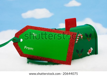 Green mailbox with blank gift tag and with the flag up sitting on snow with a snowflake background, mailbox