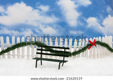 A green park benches sitting on snow with white fence and green garland on a sky background,