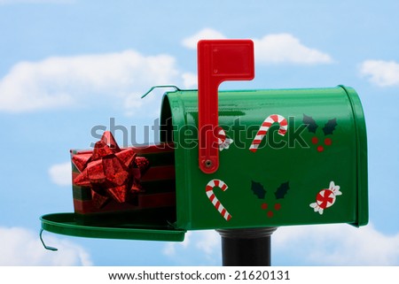 Green mailbox with a present inside and the flag up on a blue sky background, mailbox