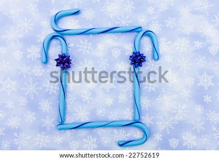 Blue candy canes with bow sitting on a blue snowflake background, candy canes