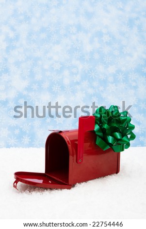 Red mailbox with green bow and the flag up sitting on snow with a snowflake background, mailbox