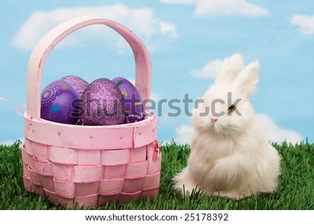 Wicker basket filled with Easter eggs and rabbit on green grass background, Easter basket
