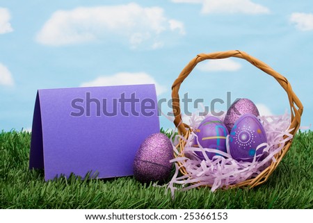 Colourful Easter eggs sitting in a basket with a blank card on green grass background, Easter basket