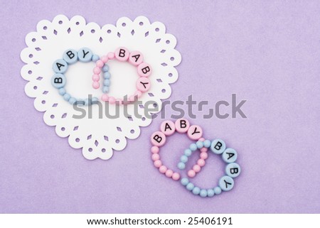 Baby bracelets sitting on a white heart on purple background, baby bracelets