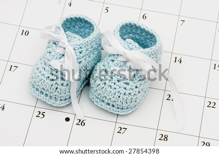 Blue baby booties on a calendar background, baby due date