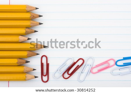 A row of wooden pencils with paperclips sitting on a paper background, School days