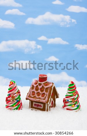 Two decorated candy Christmas trees and gingerbread house on sky background, candy Christmas tree