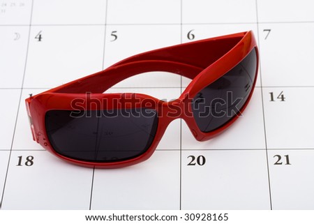 A pair of sunglasses sitting on a calendar background, vacation calendar
