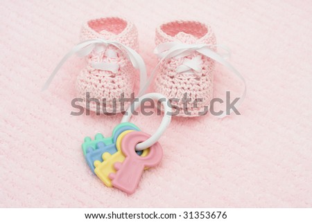 Baby booties with key rattle on a pink background, baby booties