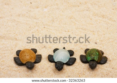 Three brown turtles with colourful shells sitting on a sand background, three turtles