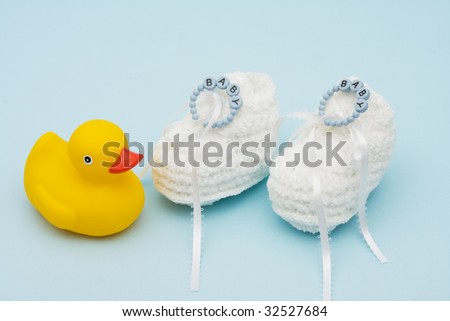 Baby booties with baby bracelet and rubber duck sitting on a blue background, baby booties