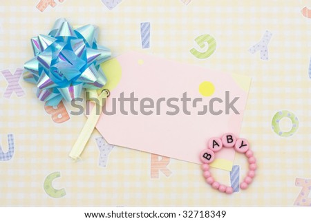 Blank tag with blue ribbon and baby bracelet sitting on a yellow alphabet background, blank tag