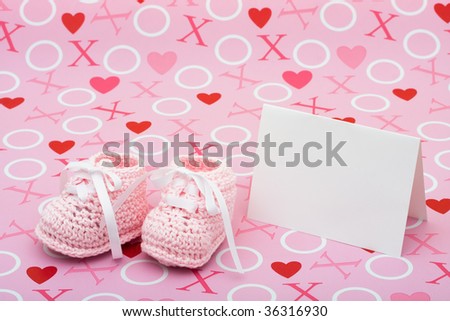 A white  card with baby booties on a pink love background, baby shower message