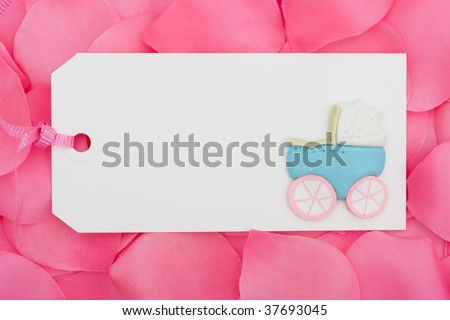 A blank gift tag sitting on a pink flower petal background, baby shower present