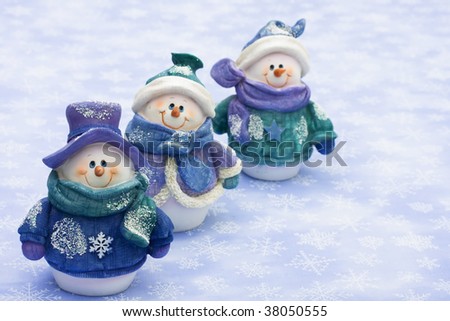 Three snowman sitting together on a snowflake background, happy holidays