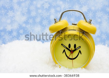 A yellow smiley face clock sitting on snow background, winter time