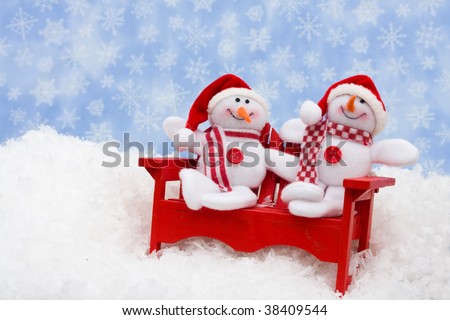 A red chair with snowmen sitting on snow with a snowflake background, happy holidays